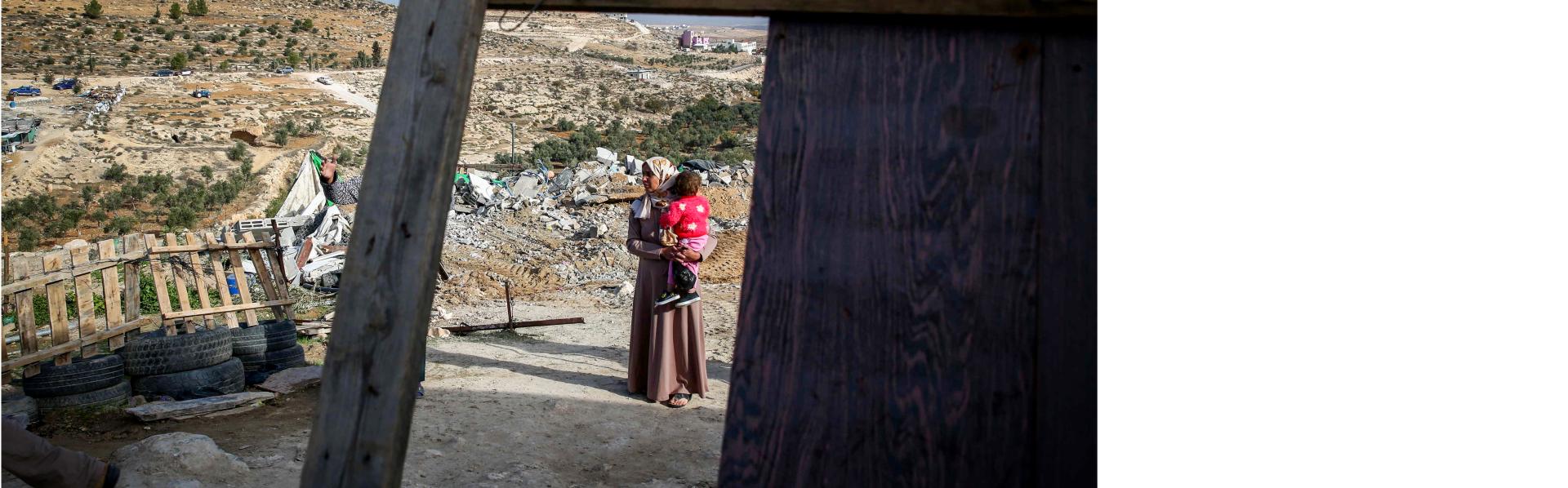 Palestijnse vrouw met baby bij haar afgebroken huis