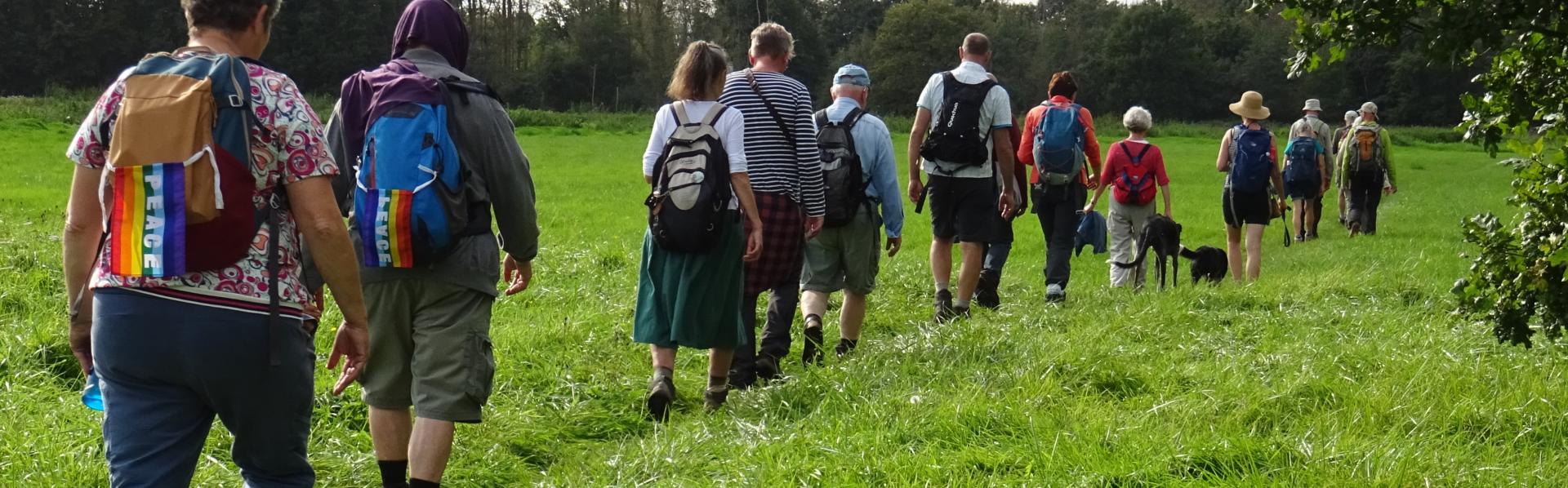 Mannen en vrouwen wandelen in een lijn door een veld voor vrede.