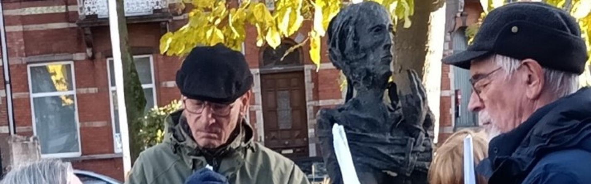 twee mannen en twee vrouwen met witte vlaggen staan bij het beeld voor de onbekende oorlogsvrouw in Hasselt. Warm ingeduffeld (de mannen dragen petten).
