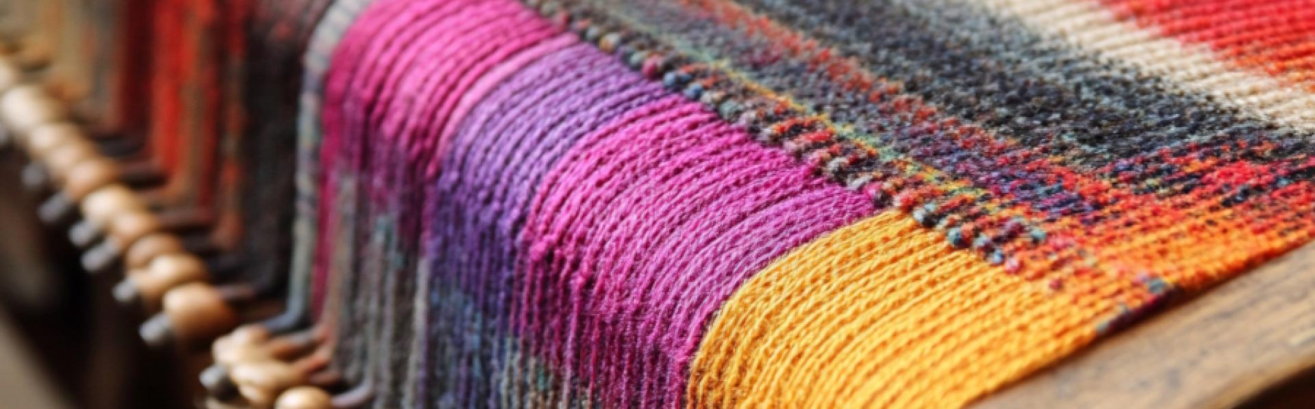 Een lap stof van veelkleurige draden op het weefgetouw