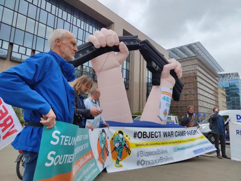 manifestanten met spandoeken 'steun zij die weigeren te doden' en grote opblaasbare gebroken geweer