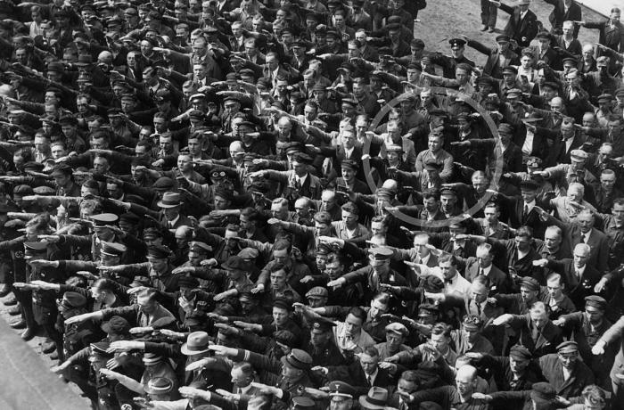 Tussen een massa mensen die de Hitlergroet brengen, staat op 13 juni 1936 August Landmesser met de armen gekruist.