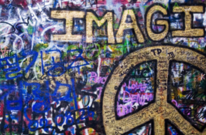 muur volgeklad met graffiti met vredesteken en het woord IMAGINE in goud geschilderd