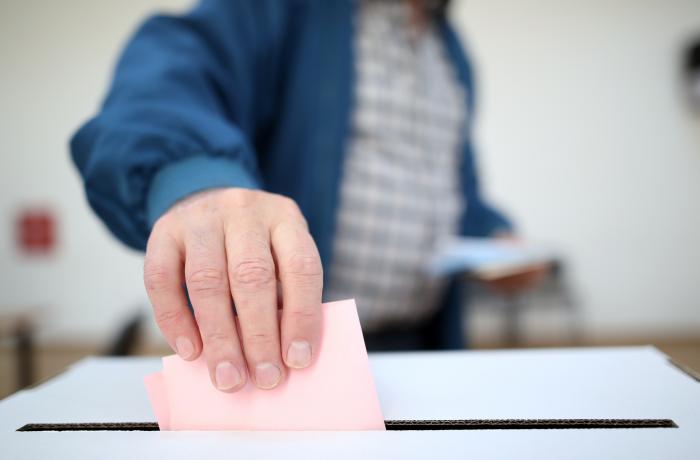 Persoon die zijn stemformulier in stembus doet