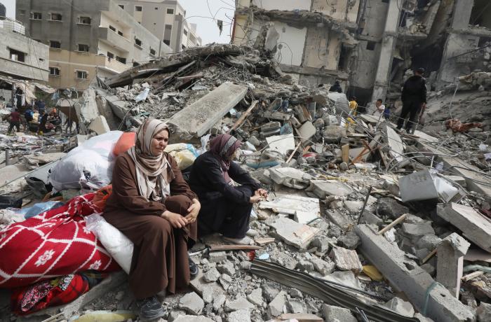 twee vrouwen zitten tussen het puin tussen ingestorte huizen in Gaza