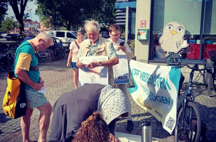Mensen tekenen een petitie tegen de oorlogseconomie aan de bib van Sint-Niklaas.