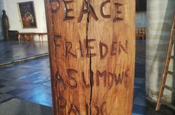 Houten stam met Vrede Peace Frieden... in verschillende talen erin gegraveerd.